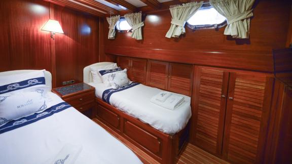 A cosy double cabin on the Gulet Ros Mare, with wooden furnishings and two single beds.