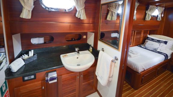 A luxurious cabin on the Gulet Ros Mare with washbasin, mirror and two single beds.