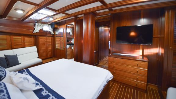 Cabin with double bed, sofa, television and elegant wooden furnishings.