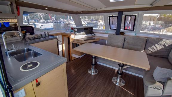 The saloon of the catamaran Sky Maria features a spacious table, seating area, and kitchen.