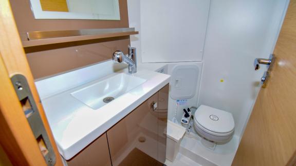 Modern bathroom with sink, toilet, and mirrored cabinet on the catamaran Sky Maria.