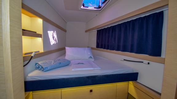 Spacious cabin on the catamaran Sky Maria with blue curtains and storage spaces.