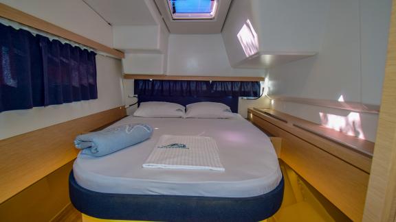 Cabin with a double bed, storage spaces, and a large skylight on the catamaran Sky Maria.