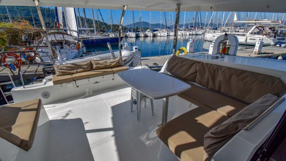 The shaded aft deck of the catamaran Sky Maria features a comfortable seating area and a table.