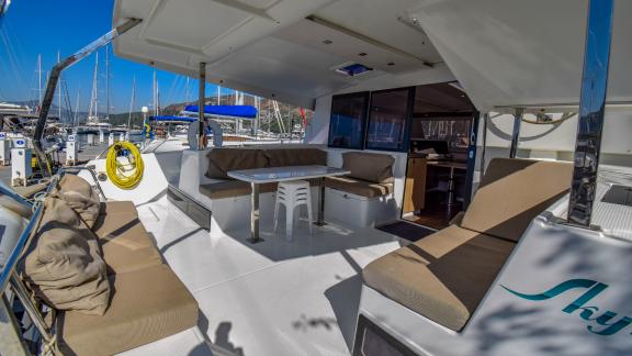 The spacious aft deck of the catamaran Sky Maria is equipped with comfortable seating areas and a table.