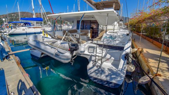 The aft deck of catamaran Sky Maria with a tender docked at the marina.