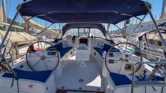 Das geräumige Cockpit der Yacht Filyos mit blauen Polstern und zwei Steuerrädern ist im Hafen vertäut.