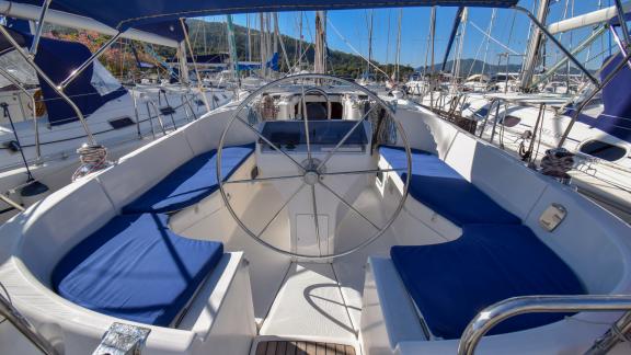 Cockpit seating area with blue cushions on the sailing yacht Burda, with the helm and surrounding yachts visible.