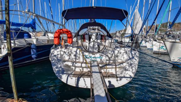 Das Achterdeck der Yacht zeigt ein blaues Sonnendach und einen orangefarbenen Rettungsring, am Steg vertäut.