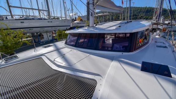 The foredeck of catamaran Coco D with a spacious seating area and sunbed, moored in the marina.