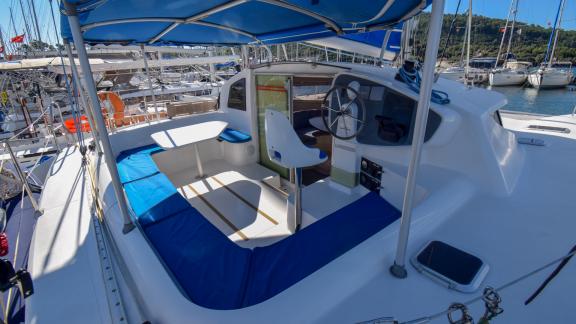 The upper deck of Andromeda catamaran features a comfortable seating area, helm, and table.