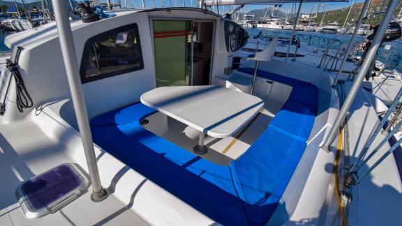 Andromeda catamaran's spacious seating area equipped with a table and cushions.