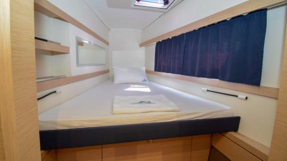 The cabin of catamaran Coco D offers a cozy bed and practical storage spaces for a restful sleep environment.