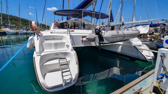 The Big Easy catamaran is anchored in the marina, with a tender boat and swim ladder on the aft deck.