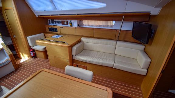Yacht saloon with soft beige sofa and large TV