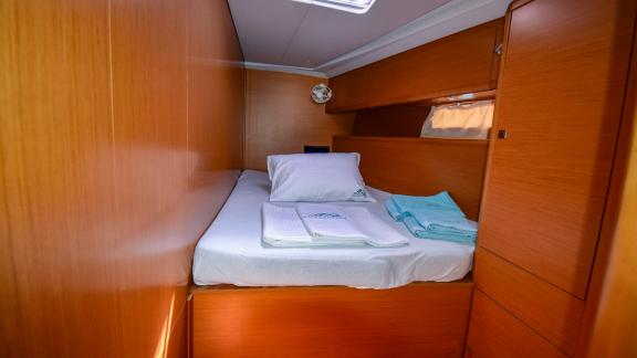 The cabin of the yacht Instant Zero offers a warm atmosphere with a comfortable bed and fresh towels.