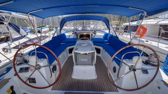 The spacious cockpit of the yacht Instant Zero features seating areas with blue cushions and two steering wheels.