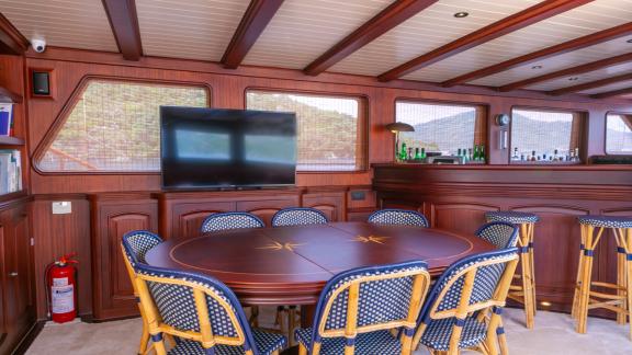 The stylish salon of the SY Voyage with a large dining table and a well-equipped bar.