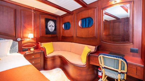 Comfortable seating area with a curved sofa and a desk in the master cabin of SY Voyage.