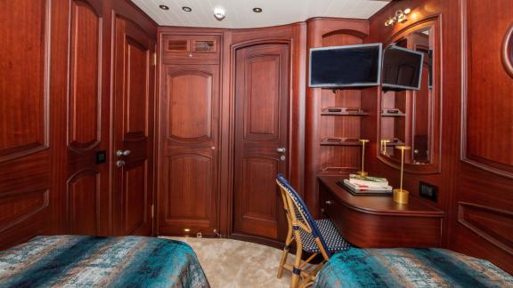 Twin cabin on SY Voyage with two beds, a desk, and a television.