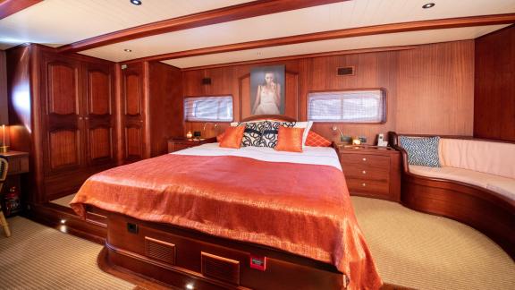 Master cabin of SY Voyage with a large bed, elegant wood decor, and a cozy seating area.