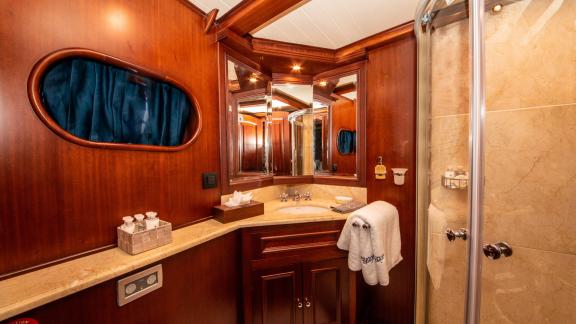 Elegantes Badezimmer der SY Voyage mit Holzverkleidung, großem Spiegel und moderner Dusche.