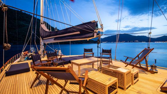 Komfortable Sitzgelegenheiten auf dem Deck der SY Voyage bei Dämmerung mit atemberaubendem Meerblick.