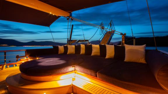 Komfortabler Loungebereich auf dem Deck der SY Voyage bei Nacht, beleuchtet mit herrlichem Blick auf das Meer.