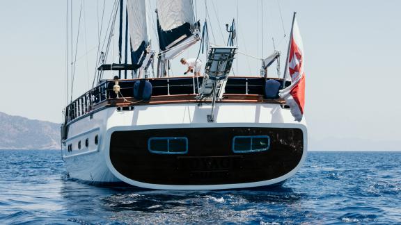 The SY Voyage sailing on open waters, its elegant aft view showcasing the yacht's quality and class.