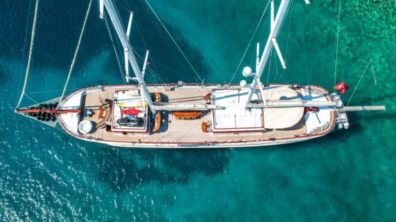 Atemberaubende Luftaufnahme einer Luxusyacht in klarem, türkisblauem Wasser.