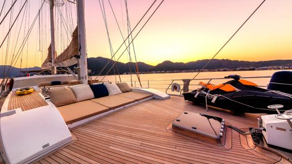 Entspannungsbereich mit Kissen und Jet-Ski auf dem Deck der Yacht Ubi Bene bei Sonnenuntergang.