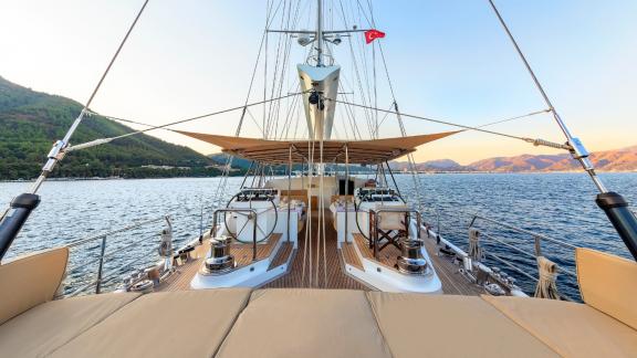 Weitläufiges Deck mit Sonnenliegen und Sitzbereich auf der Yacht Ubi Bene bei Sonnenaufgang.