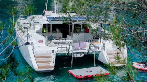Der Katamaran Marla Lagoon 450F liegt in einer ruhigen Bucht vor Anker, umgeben von üppiger Natur und klarem Wasser.