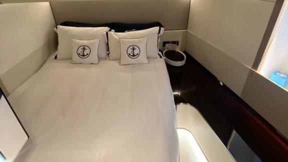 Gästekabine der Yacht Nino mit komfortablem Bett, stilvollen Kissen und modernem Design.