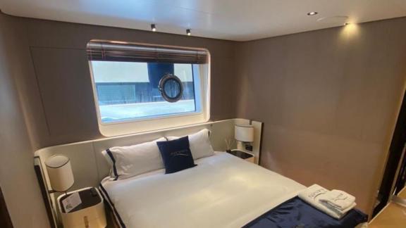 Nino yatının misafir yatak odası, geniş yatak, modern dekorasyon ve deniz manzaralı pencere ile donatılmış.