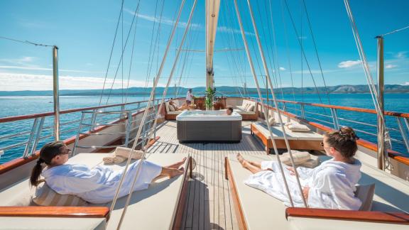 Гости отдыхают в джакузи и на шезлонгах на солнечной палубе Son de Mar с потрясающим видом на море.