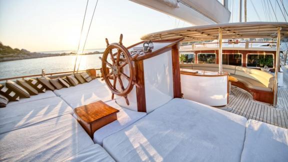 Eleganter Lounge-Bereich und Steuerstand auf einer Luxusyacht bei Sonnenuntergang.