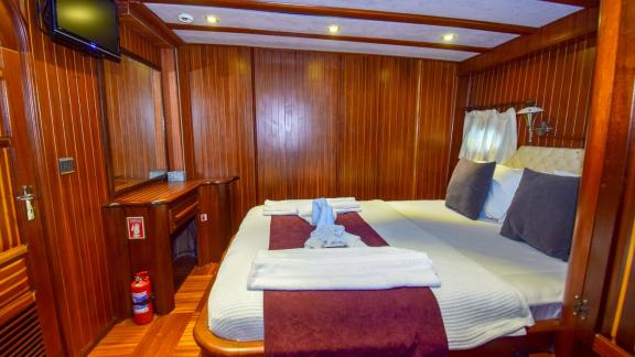 A cosy cabin on the gulet 'Ugur' with a double bed and wood panelling.