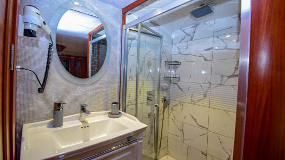 A stylish bathroom on the gulet 'Ugur' with a shower and round mirror.