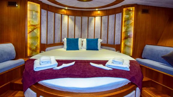 A luxurious cabin on the gulet 'Ugur' with a large, round bed and elegant lighting.