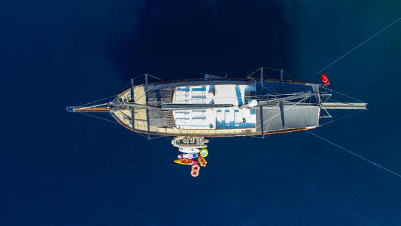 Aerial view of the gulet 'Ugur' in the turquoise blue sea of Marmaris with deckchairs and colourful water tyres.