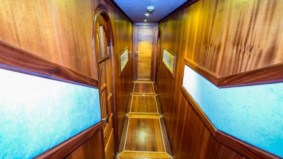 A narrow, wood-panelled corridor of the gulet 'Ugur' with doors to the cabins.