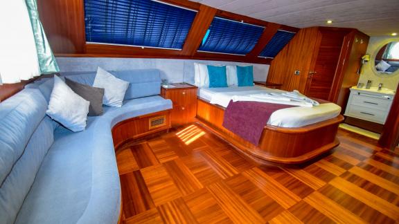 A comfortable cabin on the gulet 'Ugur' with a large bed, sofa and wooden floor.