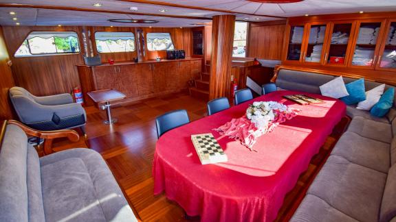 The cosy saloon of the gulet 'Ugur' with a large dining table, sofas and wood panelling.