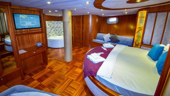 A spacious cabin on the gulet 'Ugur' with a large, round bed, a bathtub and a television.