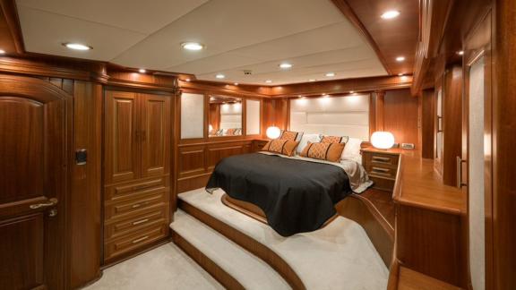 A full view of the spacious bedroom on the Kaptan Kadir gulet. You can see the bed, lots of storage space and lamps