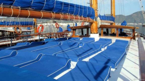 Sun deck of the gulet Bahrieli C with blue deckchairs and furled sails.