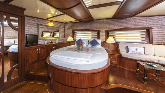 Cosy cabin with elegant bed, stylish wooden furniture and inviting lighting on board the Gulet Remzi Yılmaz.