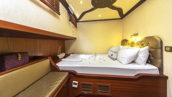 Cabin with double bed, stylish wooden furniture and inviting lighting in the Gulet Remzi Yılmaz.