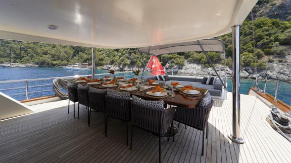 Eleganter Essbereich auf dem Außendeck der Queen of Makri, mit atemberaubender Aussicht auf das Meer und die Küste.